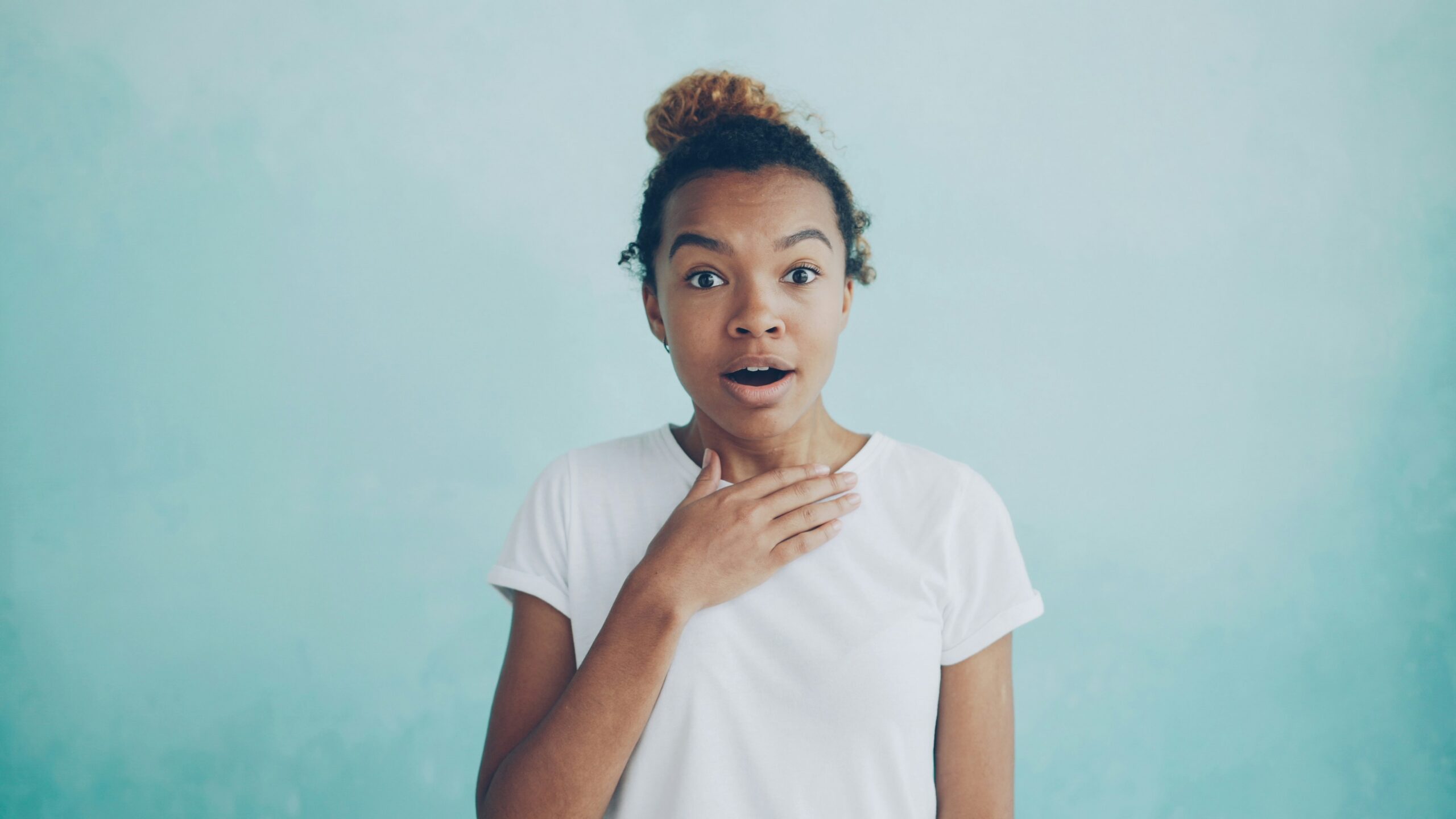 woman looking anxious while lightly touching her throat